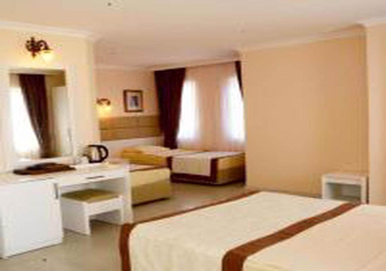 Miramor Hotel & Spa أنطاليا المظهر الخارجي الصورة The photo shows a hotel room with two beds and a cozy, inviting atmosphere. One bed is larger, possibly a queen or king size, and is draped with a light-colored bedspread that has a brown accent. The room has light-colored walls and natural light str